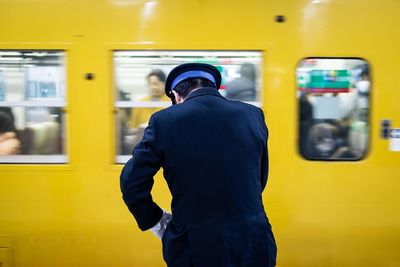 Man standing against train at railroad station