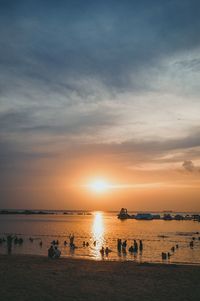 Silhouette people on beach against sky during sunset