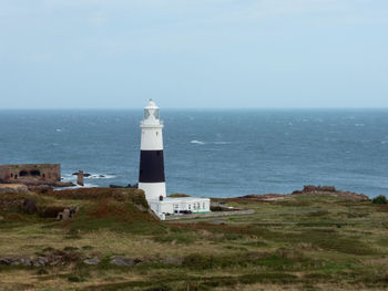 Lighthouse by sea against clear sky