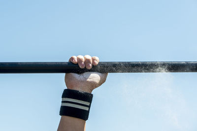 Cropped hand of woman holding rod against clear sky