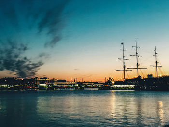 Scenic view of river by buildings against sky at sunset