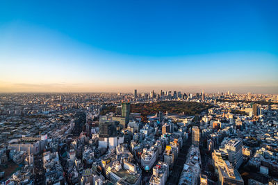 High angle view of city buildings against blue sky