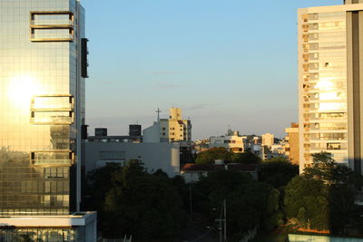 Buildings in city against clear sky during sunset