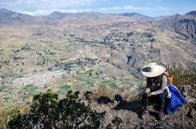 Woman using mobile phone while sitting on mountain