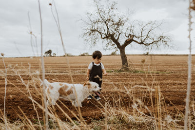 Child playing with dog on plowed field