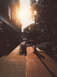 Footpath by street in city during sunset