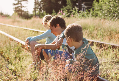 People sitting on railroad track by plants