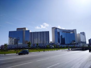 Cars on road by buildings against sky in city