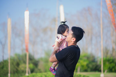 Father carrying daughter while standing in park