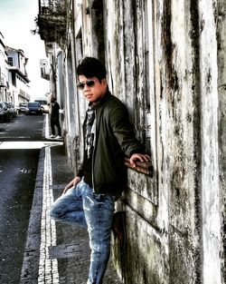 Side view of young man standing against wall