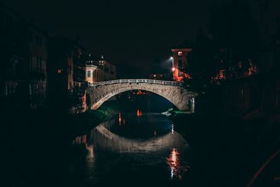 Arch bridge over river at night