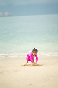 Cute girl playing with sand at beach