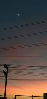 Low angle view of silhouette electricity pylon against sky during sunset