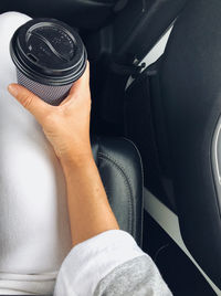 Midsection of person holding take out coffee cup in car