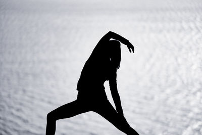 Low angle view of silhouette man with arms raised standing against sky