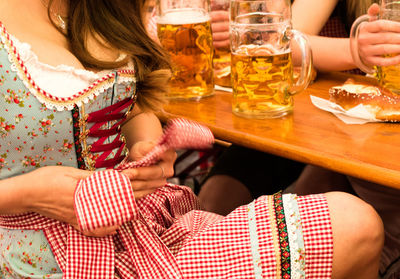 Midsection of woman adjusting dirndl by table at restaurant