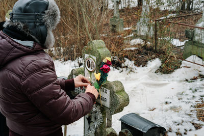 Man touching tombstone during winter