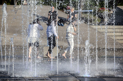 People walking by fountains in city