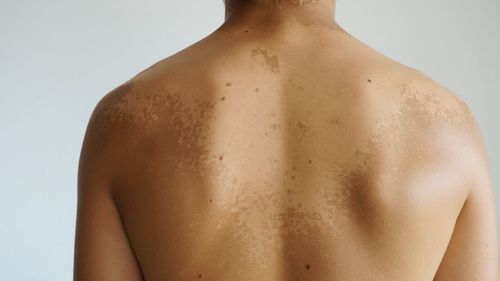 Midsection of shirtless man against white background