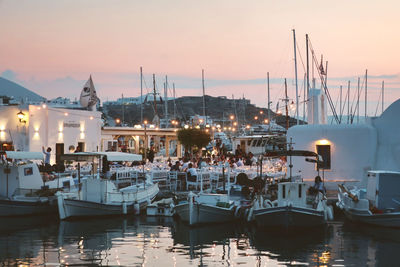 Sailboats moored in harbor at sunset