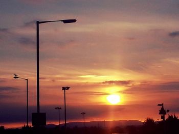 Low angle view of street lights against orange sky