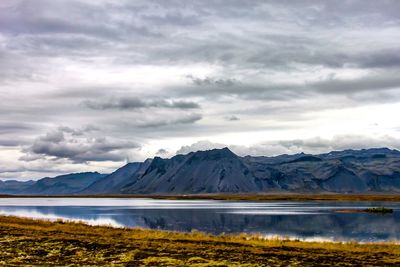 Scenic view of lake and mountains against cloudy sky