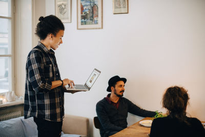 Businessman using laptop while discussing with male and female colleagues at creative office