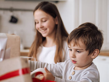 Brother and sister wrapping gift at home