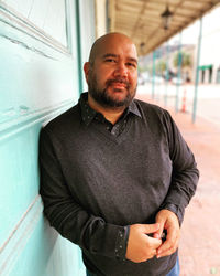Portrait of smiling young man standing against wall