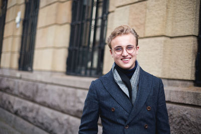 Portrait of young man standing against building