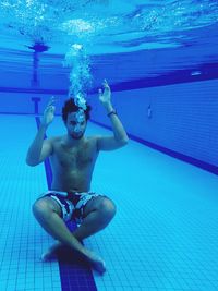 Portrait of shirtless man swimming in pool