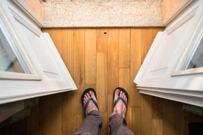 Low section of man standing on hardwood floor at home