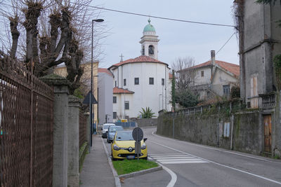 Cars on road by buildings against sky in city