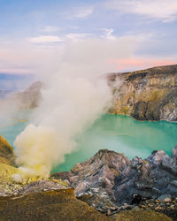 Aerial view of volcanic crater over sea against sky