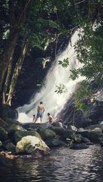 People by waterfall in forest