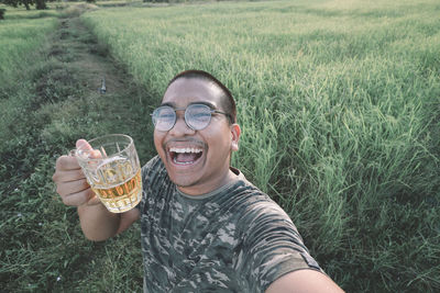 Portrait of smiling man drinking glasses on land