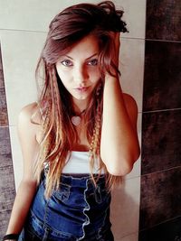 Portrait of beautiful young woman standing against wall