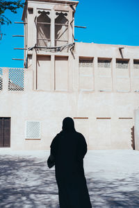 Rear view of man standing against building in city