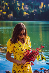 Woman with yellow flowers by lake