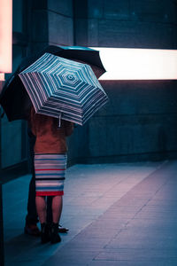 Rear view of woman standing with umbrella