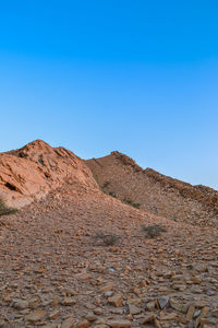 Scenic view of arid landscape against clear blue sky