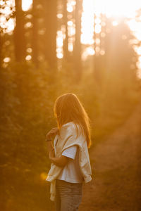 Rear view of woman standing against trees