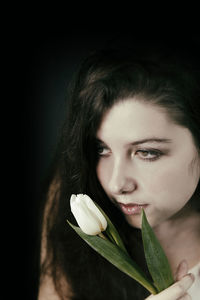 Close-up portrait of a beautiful young woman over black background