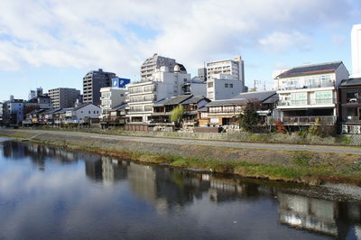 Reflection of cityscape in water against sky