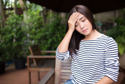 Young woman suffering from headache while sitting outdoors