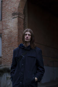 Portrait of man standing in front of brick building 