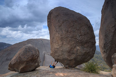 Man on cliff against cloudy sky