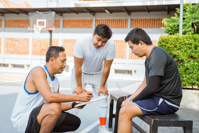 Friends sitting on seat at basketball court