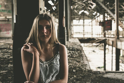 Portrait of serious woman sitting in abandoned house