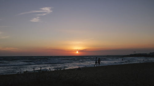 Silhouette of man standing on beach at sunset